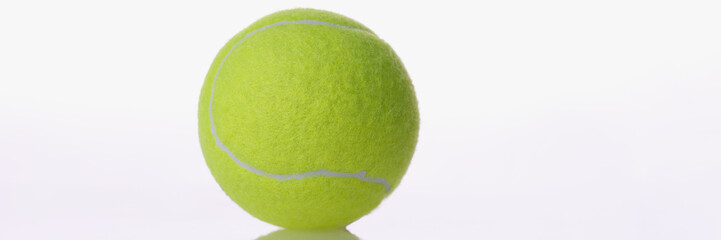 Single yellow round tennis ball sport equipment placed on reflecting surface