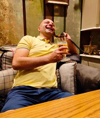 Laughing man holds a mug of beer in one hand