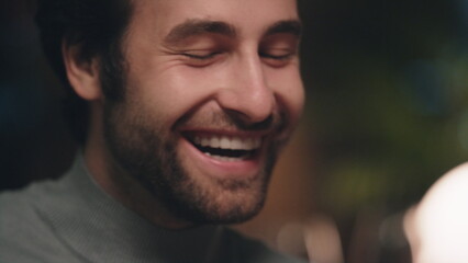 Fototapeta premium Handsome man face smiling in soft light. Positive guy enjoying conversation.