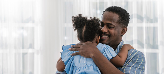Portrait of american african father daughter hugging laughing in living room. Happy daddy and...