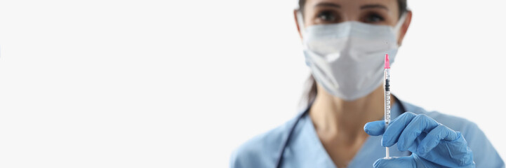 Female nurse holding syringe with vaccine liquid wear face mask