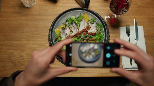 Man taking photos dinner using phone at restaurant table. Enjoy food concept.