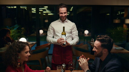 Romantic partners talking restaurant at night. Waiter serving multiracial couple
