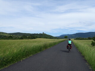Fototapeta premium Jeune femme à vélo et bicyclette avec sacoche en cyclotourisme sur les pistes cyclables et voies vertes du sud de la France région Occitanie montagne Noire Lacaune Espinouse 