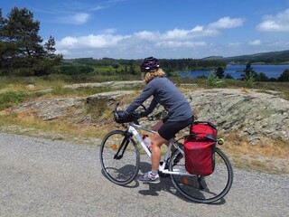 Jeune femme à vélo et bicyclette avec sacoche en cyclotourisme sur les pistes cyclables et voies...