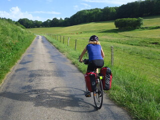 Jeune femme à vélo et bicyclette avec sacoche en cyclotourisme sur les pistes cyclables et voies...