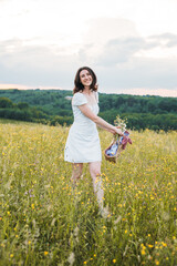 young happy female walking in the field enjoying beautiful sunset. Beautiful countryside. Slow living concept
