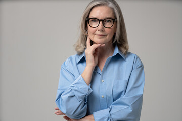 Elegant mid adult woman against white background. Stylish mature woman in blue casuals looking at camera and smiling