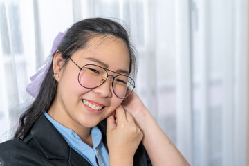 Close up to Beautiful Asian Woman face with her polite glasses in business suit in private room.