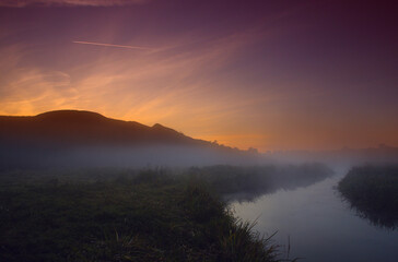 Fototapeta na wymiar Fog at dawn near the river under the mountain