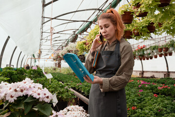 Worried woman controls the readings of measuring instruments in an industrial greenhouse and call...