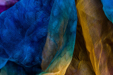 Top view photo of fabric dyed in blue and yellow and little in purple colors and laid out in an...