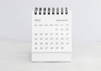 September 2022 desk calendar for planners and reminders on a wooden table on a white background - obrazy, fototapety, plakaty