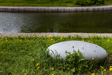 Seat in the form of a stone lies on the grass in the park (Corrected)