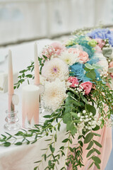 Beautiful floral arrangement and candles in candlestick on wedding table in restaurant, copy space. Luxury wedding decorations