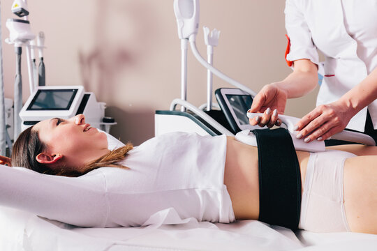 Woman getting ems treatment on abdomen to burn fat and build muscles