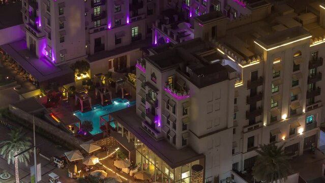 Aerial view to illuminated traditional small houses of old town island night timelapse from above. Dubai downtown with swimming pool