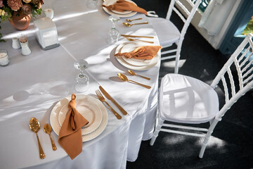 Table setting with sparkling wineglasses, plate with brown napkin and cutlery on table, copy space. Place set at wedding reception. Table served for wedding banquet in restaurant
