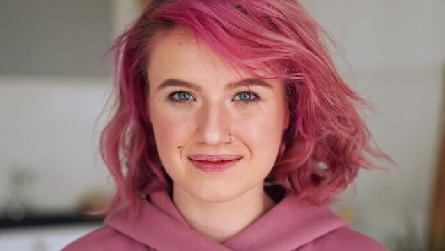 Happy teen girl with pink hair and nose piercing looking at camera. Close up portrait
