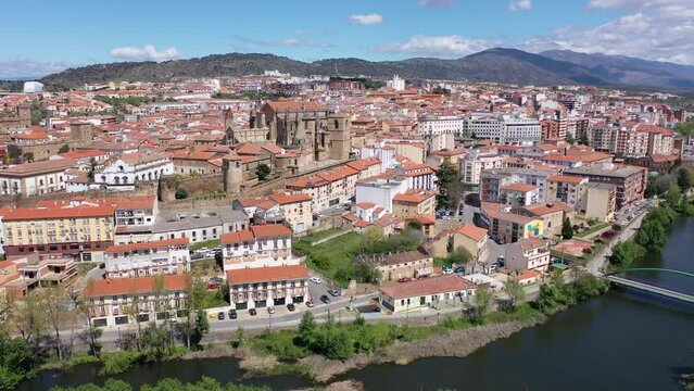 Picturesque aerial view of Plasencia city located in valley of Jerte river overlooking terracotta tiled roofs of residential buildings and medieval cathedral complex in spring, Extremadura, Spain