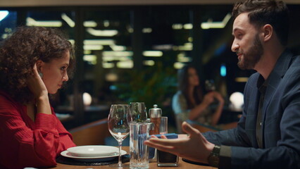 Smiling lovers talking together in night restaurant. Couple enjoy dating in bar.