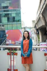 Naklejka premium Asian, Thai Chinese Woman Stands and Poses in front of the terrace with blur building background at Siam Square Area, Bangkok, Thailand. February 2022