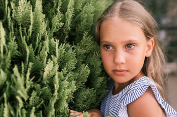 portrait face of candid offended upset little kid girl of eight years old with long blond hair and...