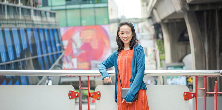 Asian, Thai Chinese Woman Stands and Poses in front of the terrace with blur building background at Siam Square Area, Bangkok, Thailand. February 2022