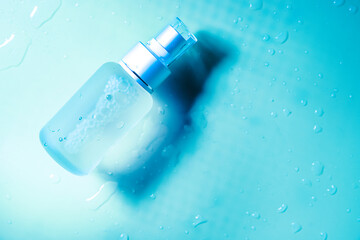 spray transparent bottle over blue background, cosmetics or body care product. High quality photo
