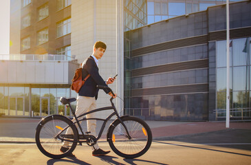 Confident young businessman walking with bicycle on the street in town