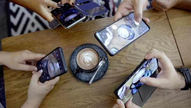 Young friends is taking pictures of coffee cup in modern cafe for bloging