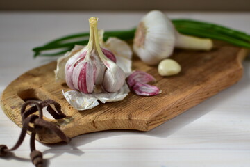 heads of garlic and green onions on a wooden board