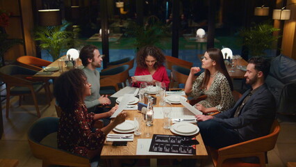 Mixed race friends talking in restaurant. People group choosing menu in cafe.
