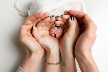 hands of parents and children. legs of a newborn in the hands of mom and dad. baby's legs in hands. child care