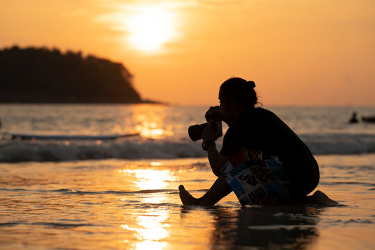 Silhouette Male Photographer on the beach with the sunset background on the horizontal line at Phuket Province, Thailand.