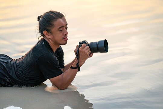 Male Photographer lays on the beach with the sunset light from behind him at Phuket Province, Thailand.