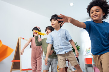 Group of Mixed race young little kid playing airplane in schoolroom.