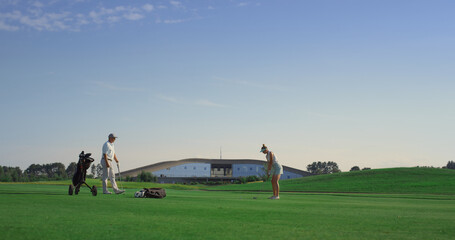 Fototapeta premium Professional golf people play game on fairway. Couple practice on sunset course.