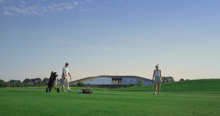 Naklejka na ściany i meble Professionals golf group play sport game on field. Business couple enjoy sunset.