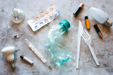 different types of garbage - plastic, batteries, light bulbs, mercury thermometer