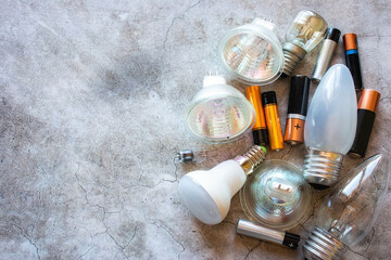 hazardous household waste - light bulbs and batteries with space for text on gray background - obrazy, fototapety, plakaty