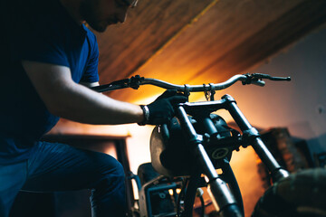 Plakat Motorcycle repair. Young man repairing motorbike in garage. Mechanic fixing motorcycle engine.