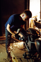 Fototapeta na wymiar Motorcycle repair. Young man repairing motorbike in garage. Mechanic fixing motorcycle engine.