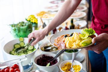 Food Buffet Catering Dining Eating Party Sharing Concept, Breakfast in the Luxury Restaurant, Man takes Food for Breakfast, Sausages, Becon, Eggs and Vegetables
