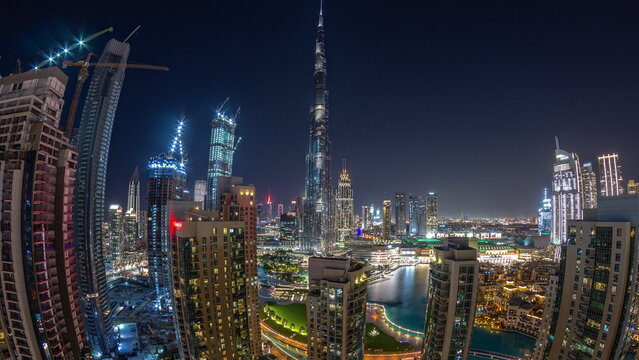 Panorama of Dubai Downtown cityscape with tallest skyscrapers around aerial night timelapse.