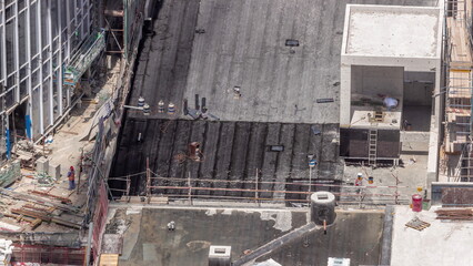 Workers working at construction site of new skyscraper and cover roof by roofing material aerial timelapse.