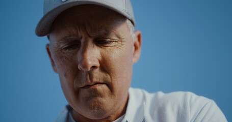 Golfing man face looking distance outdoors. Old senior wear visor cap sportswear