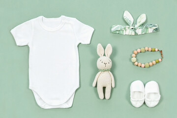 White bodysuit for baby mock-up. Mockup of infant clothes on a mint green background with baby toys...