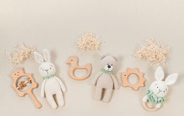 Baby toys on a pastel beige background. Wooden and knitted handmade children's toys and teethers for a banner in eco-style. Raffia clouds for composition with infant's toys and rattles.