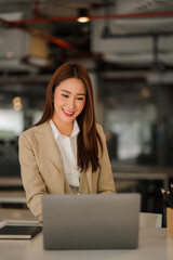 Asian businesswoman working on laptop computer in office with documents on desk woman looking at financial statistics data analysis chart profit growth business idea vertical image